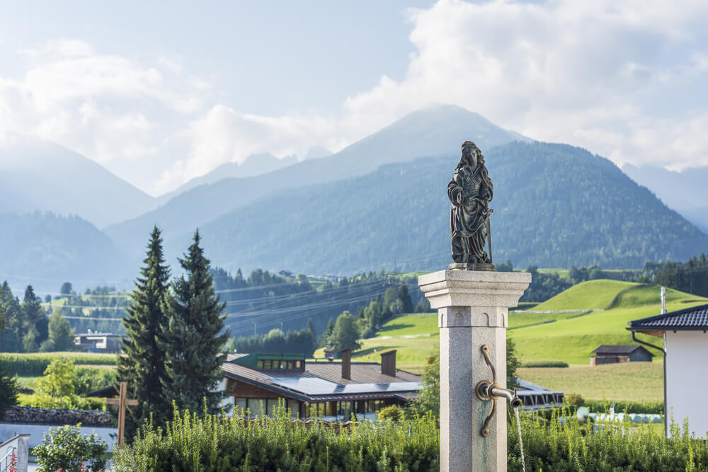 La fontaine d'Oberperfuss avec vu sur les montagnes environnantes ©Shutterstock 